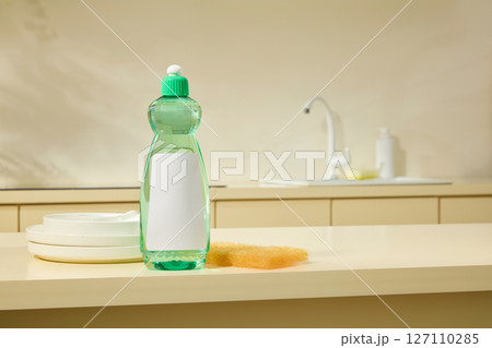 A green bottle is placed centrally on the kitchen counter with soft, natural shadows, representing cleanliness and simplicity. Scene for cleaning product advertisement, blank space for design A green bottle is placed centrally on the kitchen counter with soft, natural shadows, representing cleanliness and simplicity. Scene for cleaning product advertisement, blank space for design 127110285