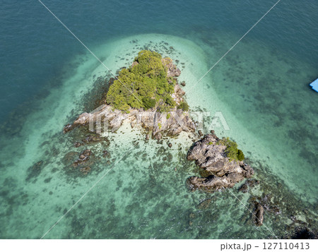 Aerial view of tropical rocky shoreline with lush island scenery, beautiful seaside landscape featuring a tranquil rocky beach with harbor and clear blue waters. Exotic shoreline scenery. 127110413