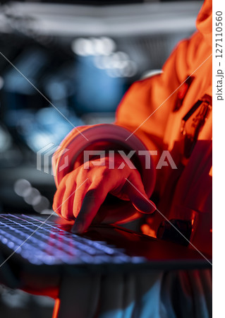 Close up of astronaut typing on laptop keyboard, troubleshooting red light warning triggered by system error. Spaceship cosmonaut using notebook to fix error affecting operations 127110560