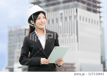 スーツにヘルメット被ってタブレットをもつ若い女性 施工管理者 現場監督 土木女子(ドボジョ) スーツにヘルメット被ってタブレットをもつ若い女性 施工管理者 現場監督 土木女子(ドボジョ) 127110641
