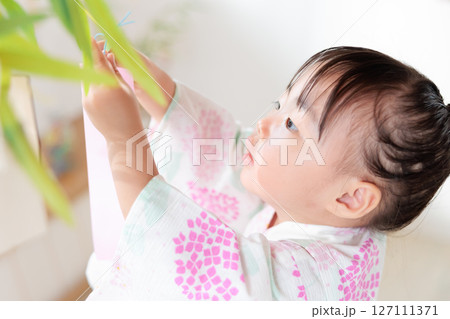 七夕　笹の葉に短冊を飾り付ける2歳の女の子　願い事　笹飾り　願いごと　一夜飾り 127111371