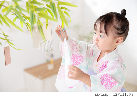 七夕　笹の葉に短冊を飾り付ける2歳の女の子　願い事　笹飾り　願いごと　一夜飾り 127111373