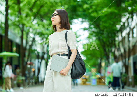 緑のある街並みを歩く女性 緑のある街並みを歩く女性 127111492