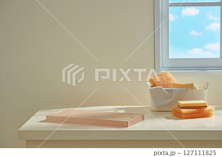 Kitchen counter with wooden board, folded cloth, and dishes arranged under a bright sky view window, evoking a serene and tidy atmosphere. Kitchen counter with wooden board, folded cloth, and dishes arranged under a bright sky view window, evoking a serene and tidy atmosphere. 127111825