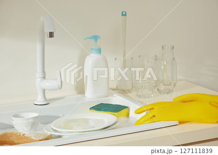 Assorted cleaning products like pump bottles, sponges, and gloves neatly displayed on a kitchen counter, set for a deep cleaning day. Assorted cleaning products like pump bottles, sponges, and gloves neatly displayed on a kitchen counter, set for a deep cleaning day. 127111839