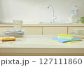 Bright kitchen sink area with stacked dishes, a sponge, and cleaning cloths styled to portray a peaceful yet functional cleaning routine. Kitchen background and blank space for design 127111860