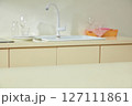 Minimalist countertop with wine glasses, a pink cloth, and a translucent spray bottle, lit by soft morning sunlight through the window. 127111861