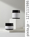Blank minimal design concept. Two amber cosmetic jars unlabeled displayed on white podiums on a white background. Front view, space for add your label 127111986