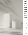 Front view of two white empty podiums displayed on a white background with natural leaves shadow. Blank minimalist empty showcase template 127111988