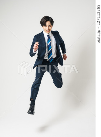 ジャンプするスーツを着た20代の若いビジネスマン 127112265