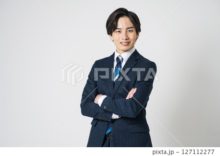 腕組みをするスーツを着た20代の若い男性 腕組みをするスーツを着た20代の若い男性 127112277