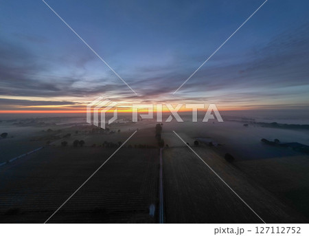 A Stunning Sunrise Over Foggy Fields Awash with Vibrant Colors Glowing Beautifully 127112752