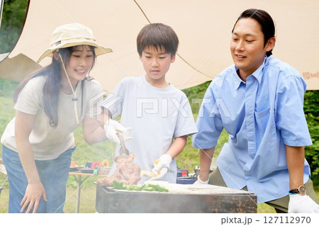 バーベキューで焼けた肉を持ち上げる子供 127112970