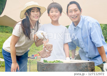 バーベキューで焼けた肉を持ち上げる子供 バーベキューで焼けた肉を持ち上げる子供 127112972