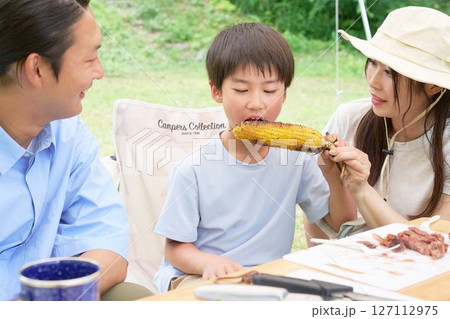 焼いたトウモロコシを食べる少年 127112975