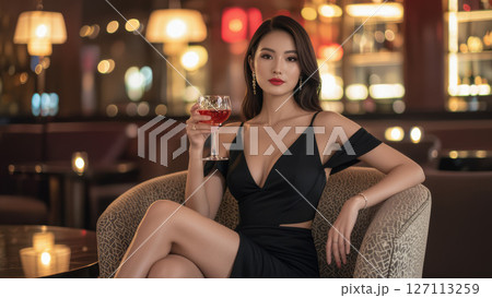 高級バーでワイングラスを持つ黒いドレスの女性 127113259