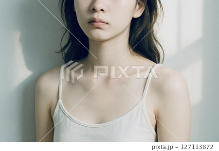 朝の光の中で壁にもたれる若い女性 127113872
