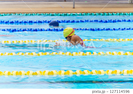 Swimmer child swims breaststroke swimming style in a race swimming pool. Water sports and competition, learning to swim classes for children. Swimmer child swims breaststroke swimming style in a race swimming pool. Water sports and competition, learning to swim classes for children. 127114596
