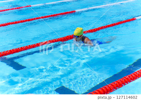 Swimmer child swims breaststroke swimming style in a race swimming pool. Water sports and competition, learning to swim classes for children. 127114602
