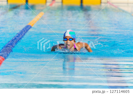 Swimmer child swims butterfly swimming style in a race swimming pool. Water sports and competition, learning to swim classes for children. 127114605