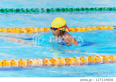 Swimmer child swims breaststroke swimming style in a race swimming pool. Water sports and competition, learning to swim classes for children. 127114608