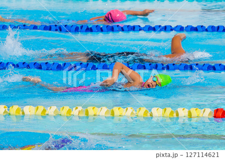 Swimmer child swims freestyle swimming style in a race swimming pool. Water sports and competition, learning to swim classes for children. 127114621