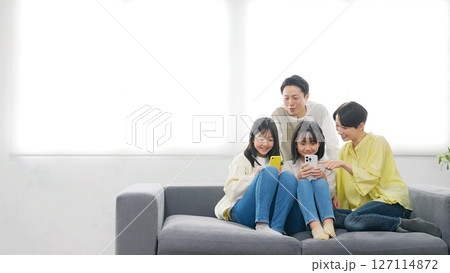 笑顔でスマホを見る小学生の女の子の家族 笑顔でスマホを見る小学生の女の子の家族 127114872