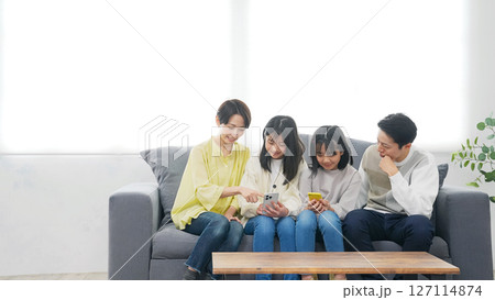 笑顔でスマホを見る小学生の女の子の家族 笑顔でスマホを見る小学生の女の子の家族 127114874
