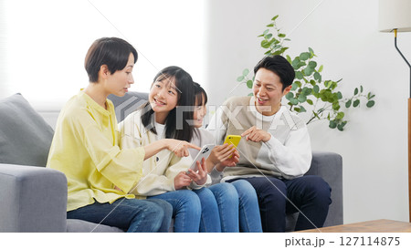 笑顔でスマホを見る小学生の女の子の家族 127114875