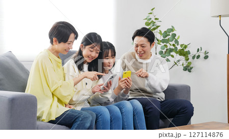 笑顔でスマホを見る小学生の女の子の家族 127114876