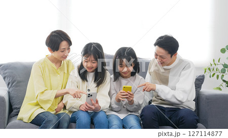 笑顔でスマホを見る小学生の女の子の家族 127114877