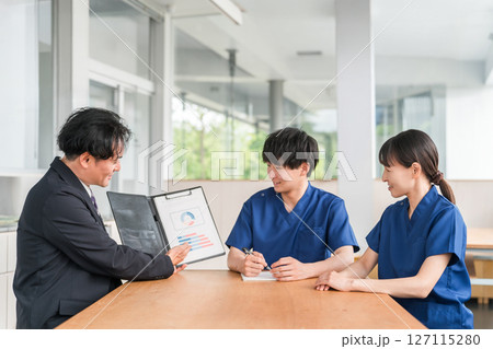 営業,商談する医療機器メーカーの男性ビジネスマンとスクラブ姿の医療従事者の男女 営業,商談する医療機器メーカーの男性ビジネスマンとスクラブ姿の医療従事者の男女 127115280
