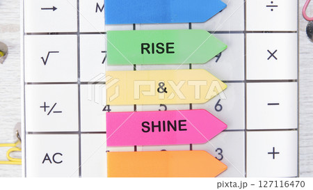 Growth Success Achievement Progress Concept. Words RISE AND SHINE motivating messages are placed on the calculator on bright stickers 127116470