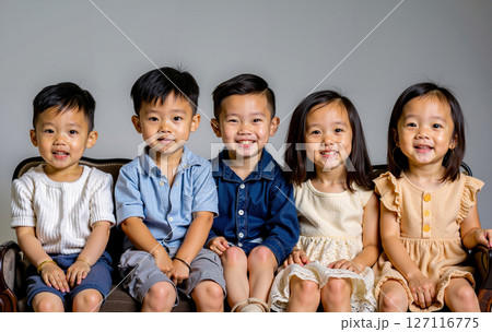 A group of children sitting on a couch smiling at the camera A group of children sitting on a couch smiling at the camera 127116775