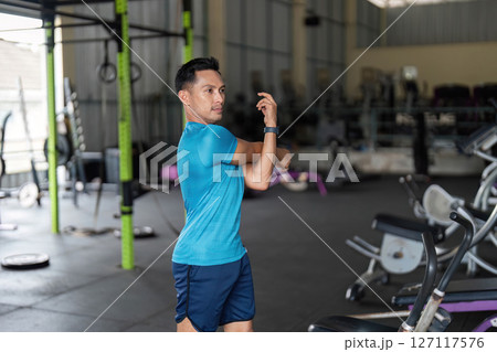 Fitness Warm-Up: Man Stretching Arm in Gym 127117576
