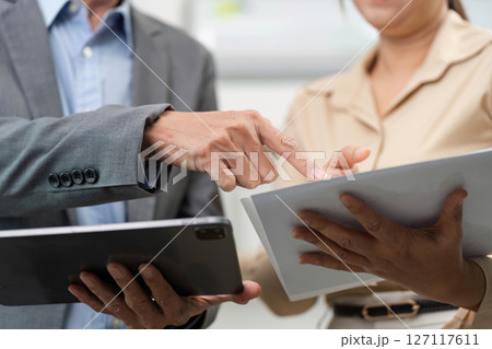 Close-Up of Professional Interaction. Business partners discussing data on tablets. 127117611