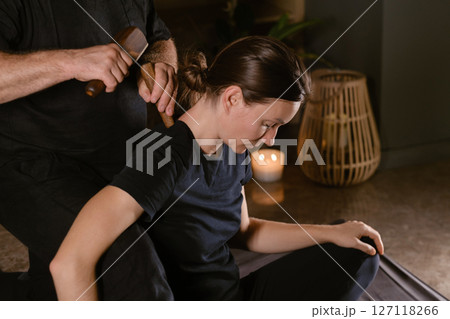 Male master giving Thai Toksen massage to girl in massage room. A girl gets a relaxing Thai back massage with a Toxen massage kit Male master giving Thai Toksen massage to girl in massage room. A girl gets a relaxing Thai back massage with a Toxen massage kit 127118266