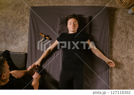 A man gives a relaxing Thai massage on his arm with a Tok-Sen massage kit at a beauty salon. Body care 127118302