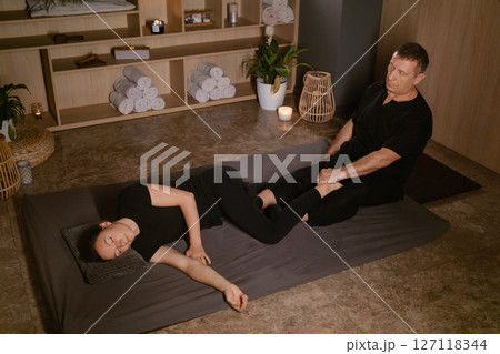 Girl in Thai massage session from therapist in massage room . Traditional Asian stretching therapy 127118344