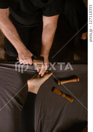A man gives a relaxing Thai foot massage with a Tok-Sen massage kit at a beauty spa. Body care A man gives a relaxing Thai foot massage with a Tok-Sen massage kit at a beauty spa. Body care 127118355