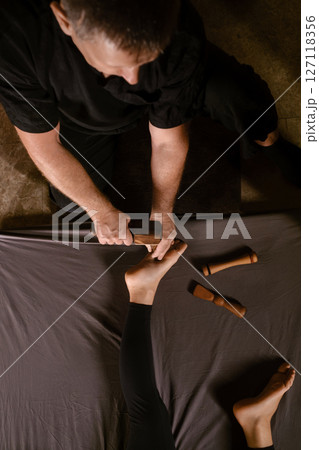 Massage therapist performs a relaxing Thai foot massage using a Tok-Sen massage set at the spa. Body care 127118356