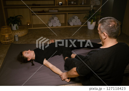 Girl in Thai massage session from therapist in massage room . Traditional Asian stretching therapy 127118423