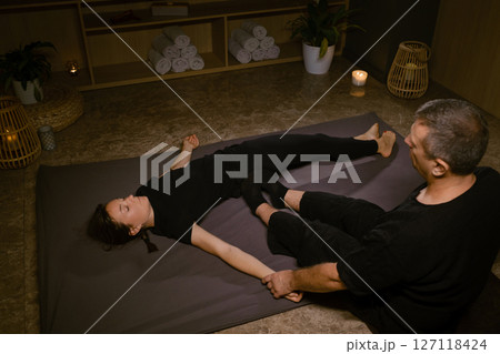 Professional masseur gives Girl Thai massage in massage parlor. Traditional Asian stretching therapy 127118424
