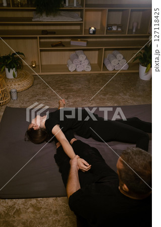Girl in Thai massage session from therapist in massage room . Traditional Asian stretching therapy Girl in Thai massage session from therapist in massage room . Traditional Asian stretching therapy 127118425