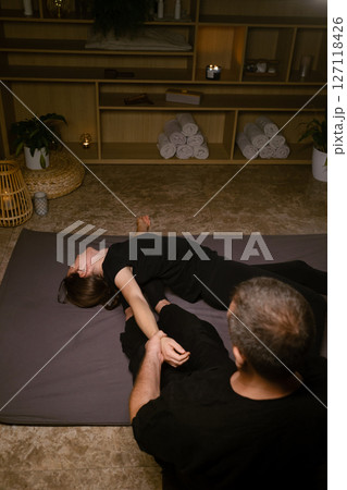 Girl in Thai massage session from therapist in massage room . Traditional Asian stretching therapy Girl in Thai massage session from therapist in massage room . Traditional Asian stretching therapy 127118426