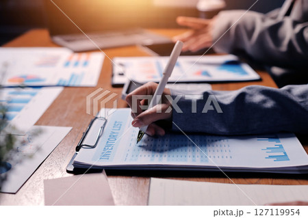 Group of confident business people point to graphs and charts to analyze market data, balance sheet, account, net profit to plan new sales strategies to increase production capacity. 127119954