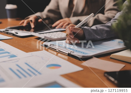 Group of confident business people point to graphs and charts to analyze market data, balance sheet, account, net profit to plan new sales strategies to increase production capacity. 127119955