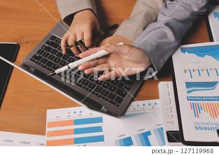 Group of confident business people point to graphs and charts to analyze market data, balance sheet, account, net profit to plan new sales strategies to increase production capacity. 127119968