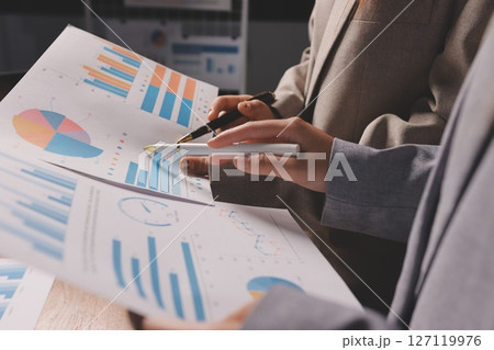 Group of confident business people point to graphs and charts to analyze market data, balance sheet, account, net profit to plan new sales strategies to increase production capacity. 127119976