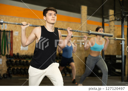 Motivated CrossFit male athlete lifting heavy body bar or barbell during group training in gym. Functional training concept 127120497